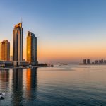 Vue panoramique de Manama au coucher du soleil, avec la baie calme, les gratte-ciel modernes illuminés et une atmosphère élégante au Bahreïn.