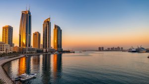 Vue panoramique de Manama au coucher du soleil, avec la baie calme, les gratte-ciel modernes illuminés et une atmosphère élégante au Bahreïn.